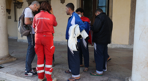 Migranti e operatori della Croce Rossa davanti all'entrata della Prefettura di Belluno