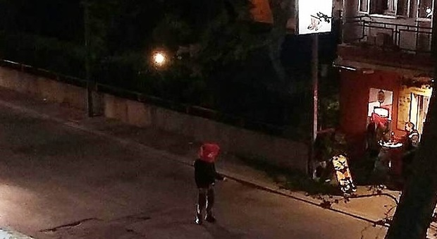 Il ragazzo attraversa la strada con il sacchetto in testa