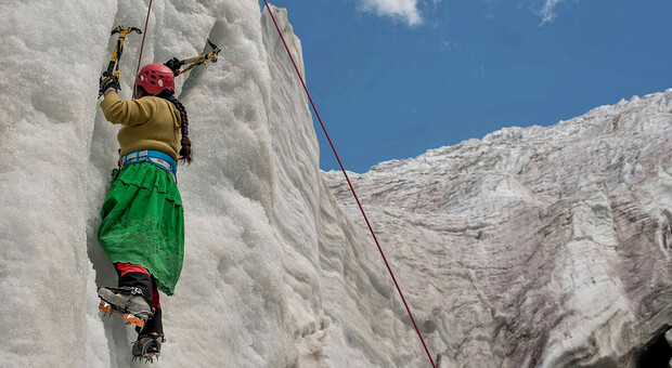 Una delle Cholitas arrampica su una parete di ghiaccio