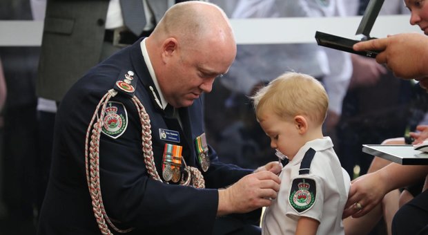 Il bambino di 19 mesi decorato con un ciuccio al funerale del papà pompiere, morto per spegnere i roghi