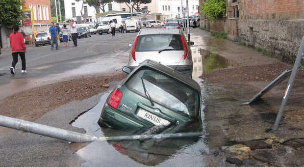 Roma, si apre una voragine in strada: Un'auto ci cade dentro. Strade chiuse e allagate