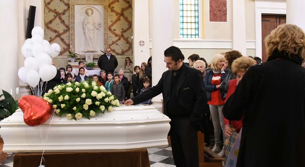 Papà Carlo durante il rito funebre con la mano appoggiata alla bara bianca di Sasha