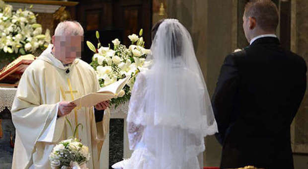 Sposi novelli kissing mentre si esce dalla chiesa dopo la cerimonia di  matrimonio, la famiglia e