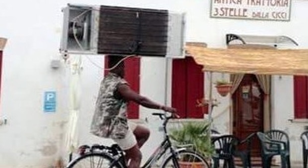 Migrante "equilibrista": in bici col frigorifero sulla testa. La foto fa il giro del web