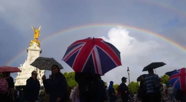 A Buckingham Palace la folla in lacrime canta 'God save the Queen'. E in cielo appare un arcobaleno