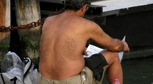 Uomo legge il giornale a torso nudo