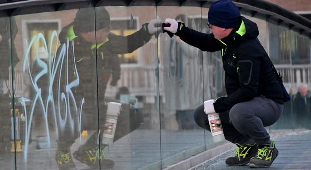 Un ragazzo pulisce il parapetto in vetro del ponte