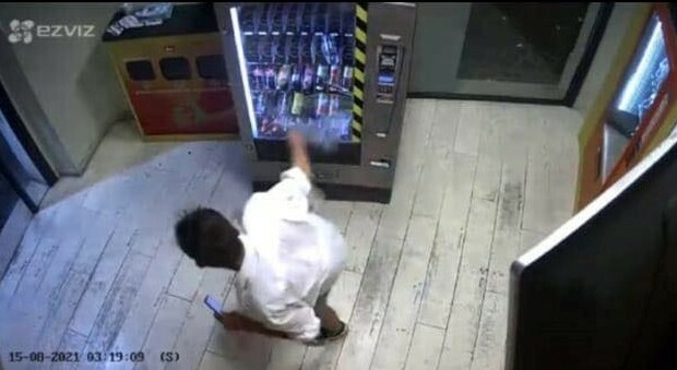 Un ragazzo mentre sferra un calcio a un distributore automatico