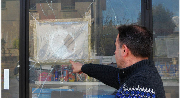 Il titolare della cartolibreria "Sacart" mostra la vetrina colpita da un sasso