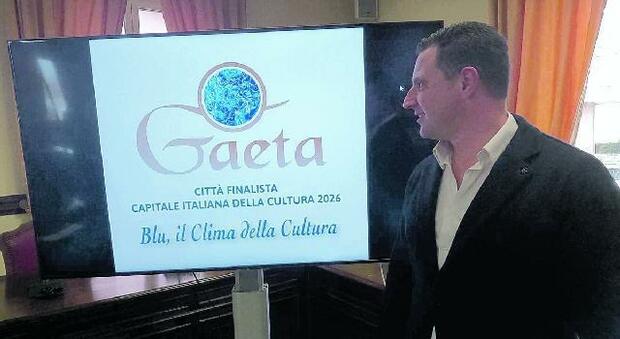 Il sindaco di Gaeta Cristian Leccese davanti al logo della candidatura di Gaeta a Capitale italiana della Cultura