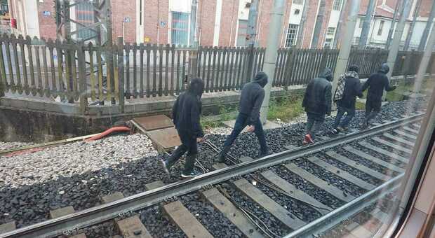 Migranti camminano lungo la ferrovia a Udine
