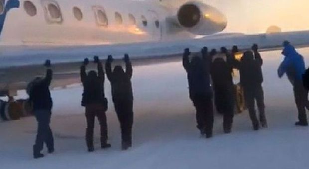 Passeggeri spingono a braccia aereo bloccato sul ghiaccio