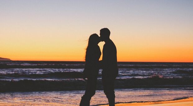 Una coppia al mare che si bacia durante il tramonto