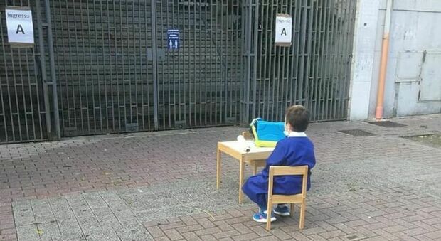 Bimbo seduto davanti alla scuola chiusa, la foto simbolo fa il giro del web