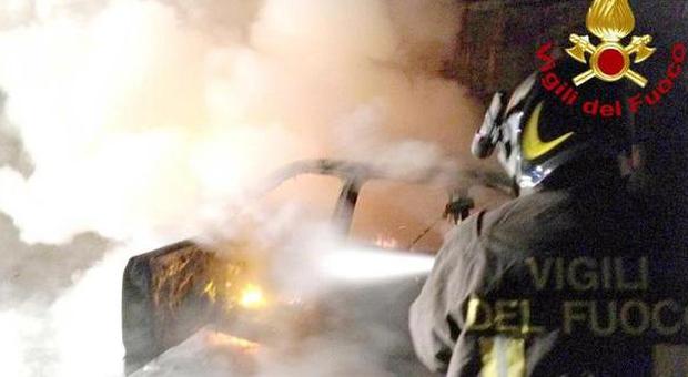 Un vigile del fuoco impegnato a domare l'incendio di un'auto