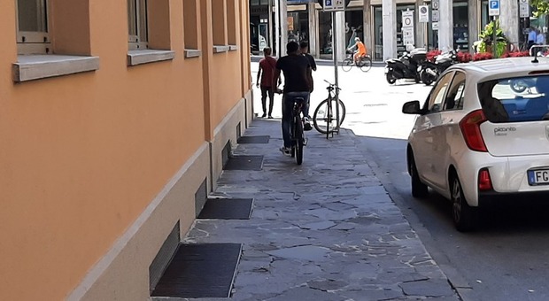 In bicicletta sul marciapiede e dall'altra parte della strada c'è la ciclabile