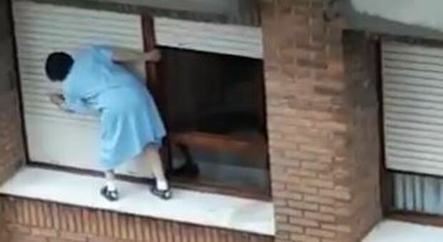 Donna in equilibrio sul davanzale al settimo piano per pulire le persiane: il vertiginoso video virale