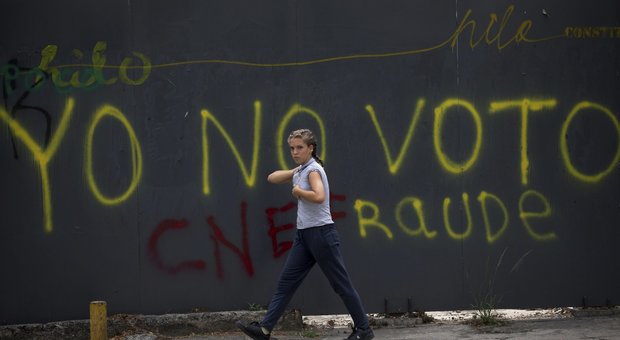 Un pedone cammina davanti a un graffito a Caracas