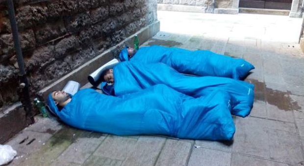 Ragazzi dormono con il sacco a pelo in una calle
