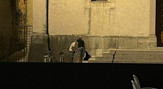 Un'immagine del 20enne che, steso sui gradini del Duomo, viene svegliato da due amici quando sono
