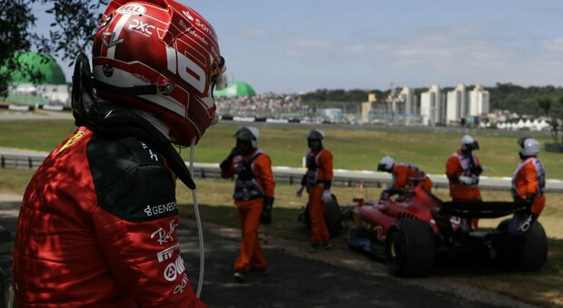 Leclerc guarda sconsolato i commissari che spostano la Ferrari fuori uso in Brasile