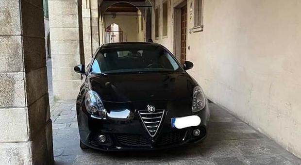 La scintillante Alfa Romeo parcheggiata con cura occupa tutla la larghezza dei portici di via San Pietro