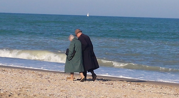 Due anziani a passeggio sulla battigia