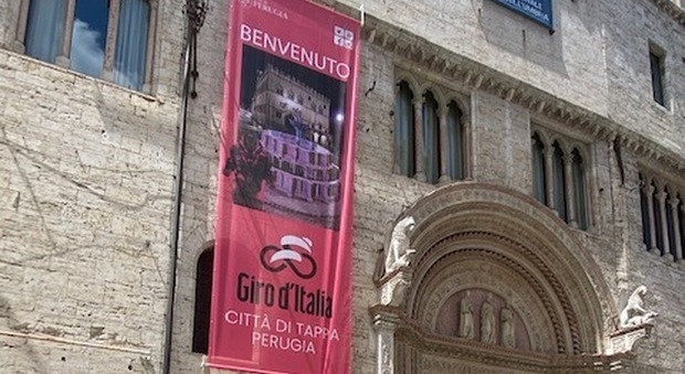 Lo stendardo appeso a palazzo dei Priori annuncia l'arrivo del Giro d'Italia in città
