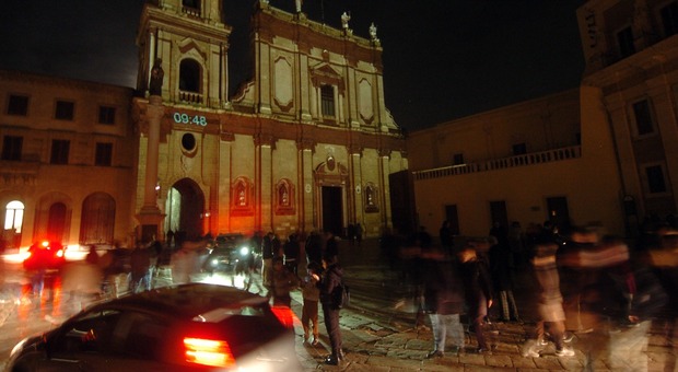 Auto in transito accanto alla cattedrale, sulla cui facciata è proiettato ogni 10 minuti uno spettacolo di video mapping