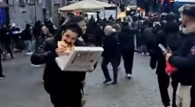 Ragazzo mangia la pizza durante gli scontri