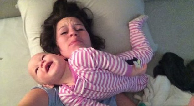La bimba fa di tutto per svegliare la mamma: tra dita nel naso e prese da wrestling il video è virale