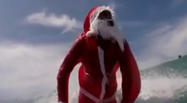 Brasile, Babbo Natale sfida le onde e arriva col surf