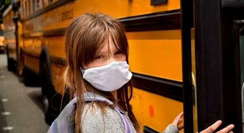 Una bambina sta per entrare in uno scuolabus