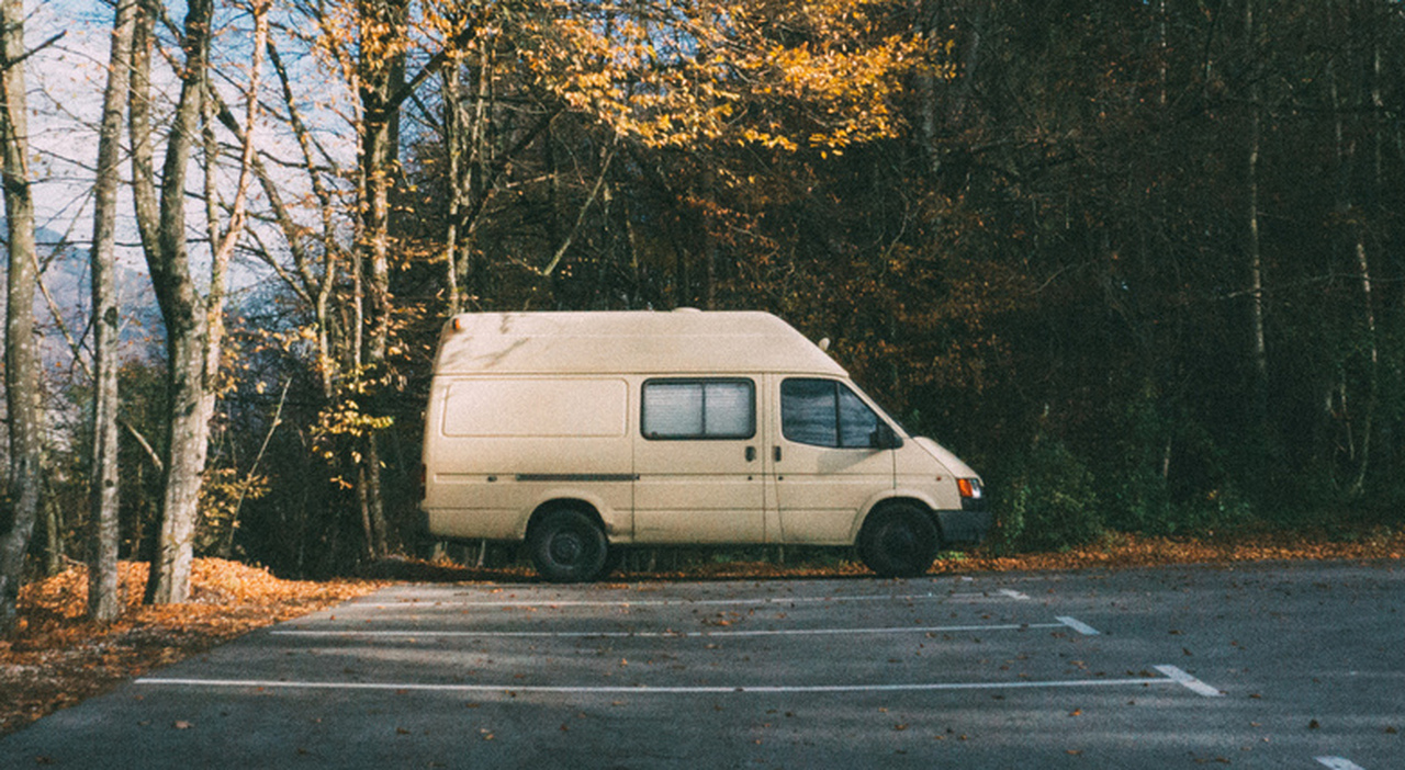 https://statics.cedscdn.it/photos/MED_HIGH/2026/04/12/9470336_12165151_motorhome_parked_parking_lot_forest_camping_adventure_concept.jpg