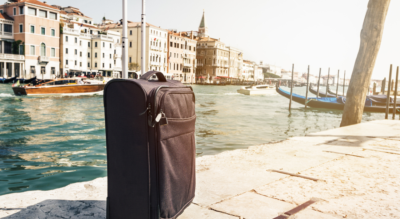 https://statics.cedscdn.it/photos/MED_HIGH/2026/05/27/9558329_27201112_small_suitcase_travel_urban_background_venice_italy_horizontal_toning_travel_vacation_concept.jpg