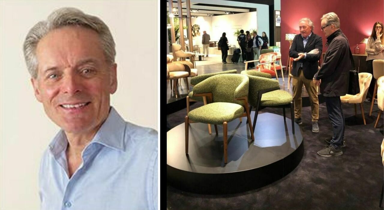 Un uomo seduto in un ambiente domestico, con un progetto di design sul tavolo, mentre i familiari lo circondano con affetto