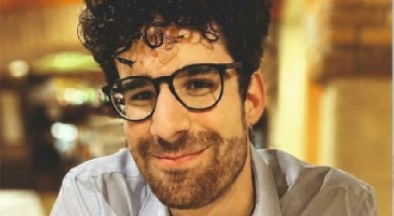 Un giovane motociclista riverso a terra dopo un grave incidente stradale, con automobilisti che chiamano i soccorsi