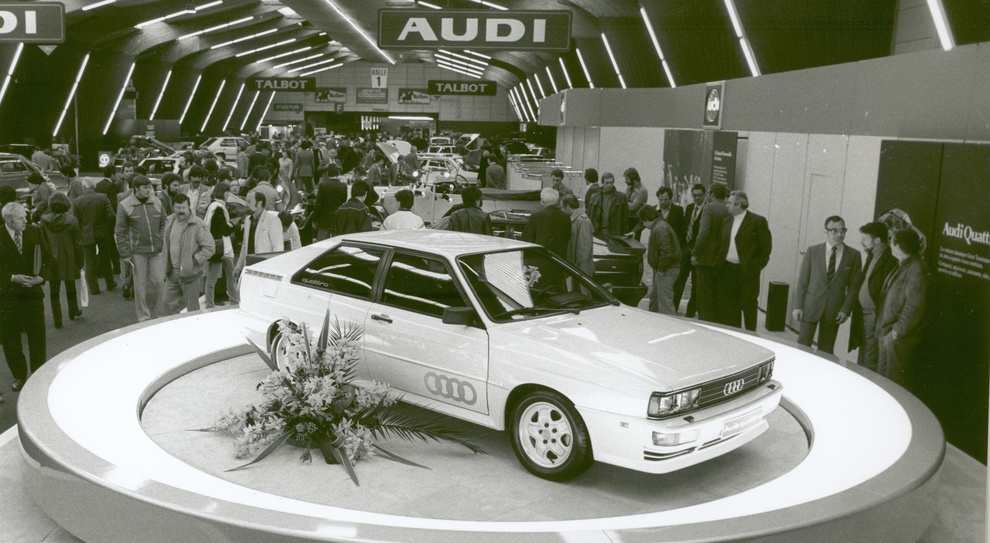 La prima pietra fu posata nel 1980 al Salone di Ginevra con l’Audi Quattro, un coupé dotato di motore 5 cilindri 2.1 da 200 cv e trazione integrale permanente
