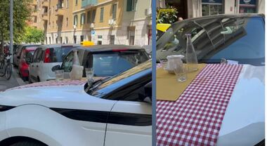 Parcheggia l'auto davanti al ristorante, i passanti apparecchiano sul cofano con tovaglia e bicchieri: il video sui social