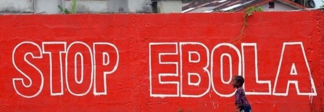 Un bambino in Liberia cammina lungo un enorme striscione che avverte la popolazione Un bambino in Liberia cammina lungo un enorme striscione che avverte la popolazione