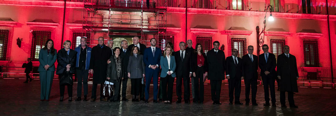 Giorgia Meloni posa con i ministri davanti a Palazzo Chigi illuminato di rosso